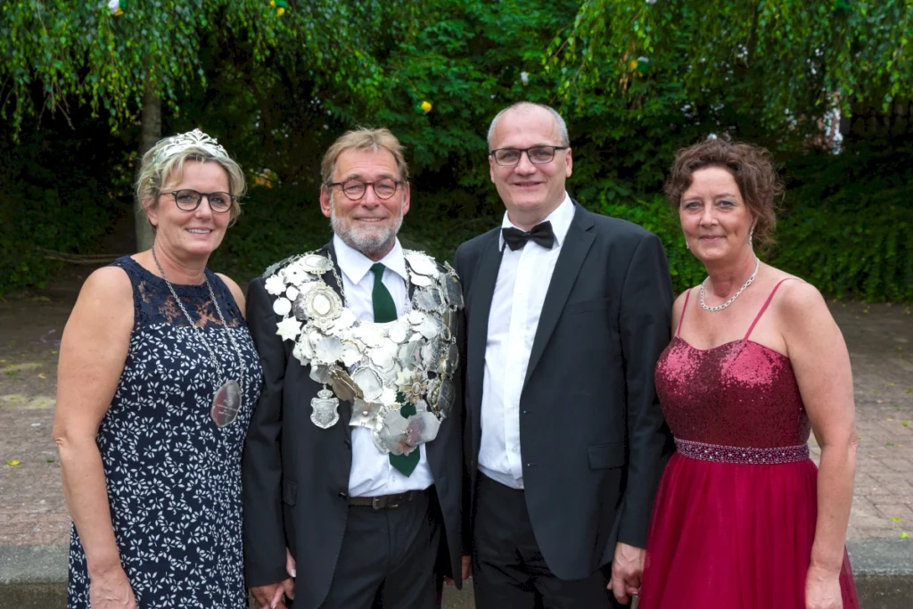 "Vier Mitglieder der Schützengesellschaft Freren in festlicher Kleidung, posieren gemeinsam im Freien. Der Träger der Schützenkette steht im Mittelpunkt, umgeben von Damen in eleganten Abendkleidern. Ein Symbol für Gemeinschaft und Tradition beim Schützenfest."